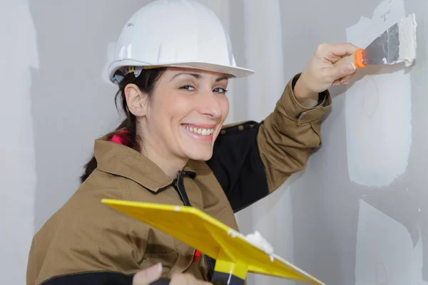 Yesero femenino haciendo una renovación de la pared con espátula y yeso — Foto de Stock