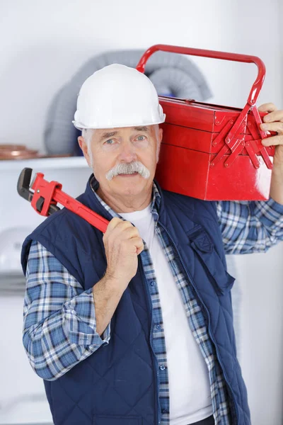 Feliz trabajador senior sosteniendo caja de herramientas y llave inglesa — Foto de Stock