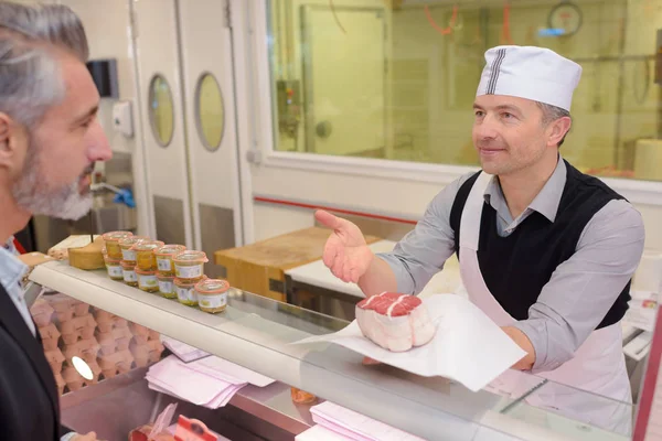 Řezník porci zákazníka a řezník — Stock fotografie