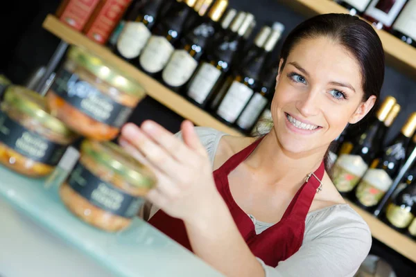 Szczęśliwy ekspedientka stojąc przed półkami w sklepie wina — Zdjęcie stockowe
