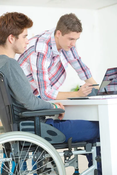 친구는 숙제를 하 고 휠체어에 젊은 남성 — 스톡 사진