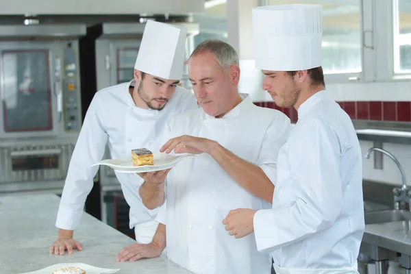 Koch und Assistenten bei der Arbeit in der Küche — Stockfoto