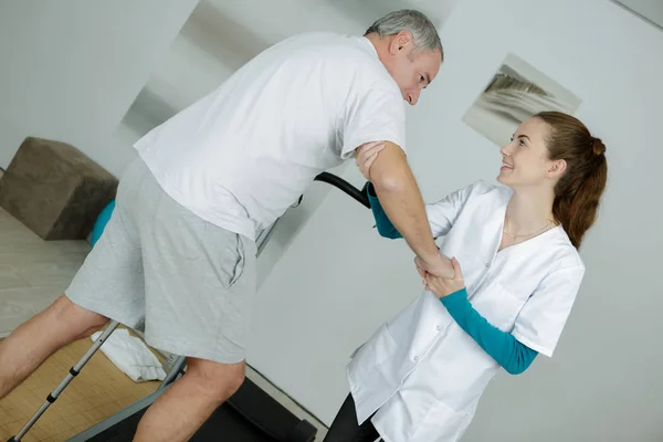 Physiothérapeute féminine debout à côté du patient marchant entre paral — Photo