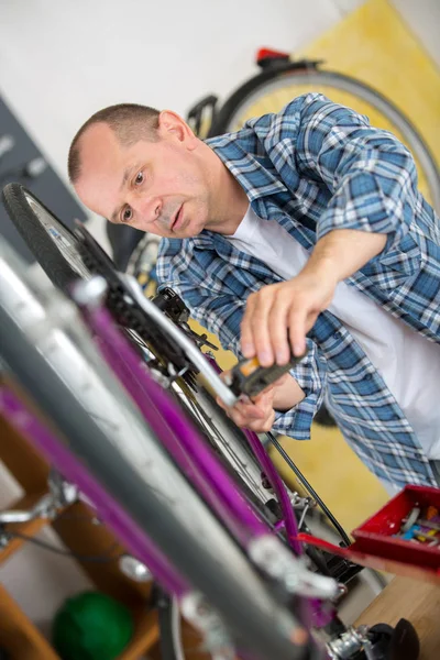 Mogen man reparerade cykel i sin verkstad — Stockfoto