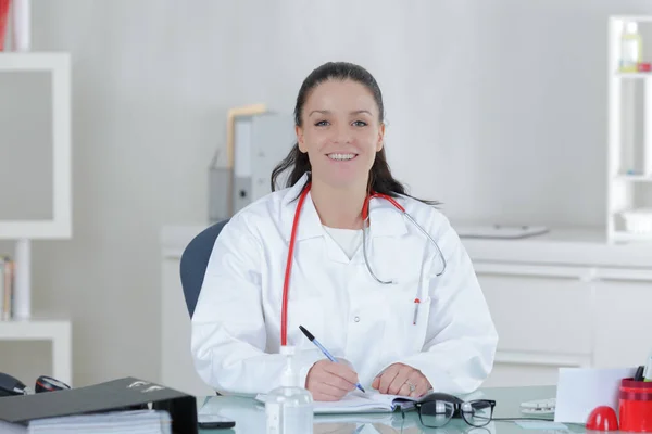 Retrato de una joven doctora sentada en el escritorio del hospital —  Fotos de Stock