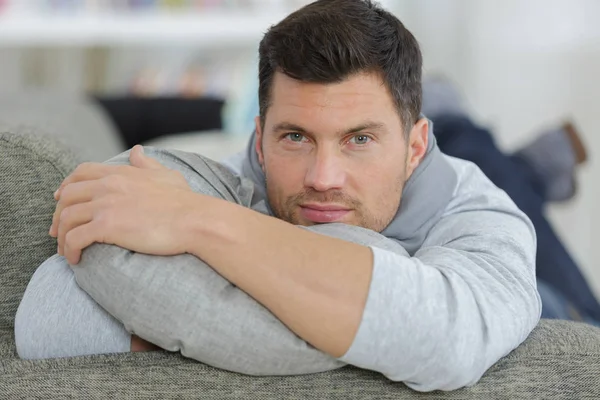 Junger schöner Mann entspannt sich auf seinem Sofa — Stockfoto