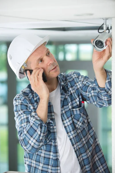 Зрелый мужчина-техник устанавливает камеру на телефон — стоковое фото