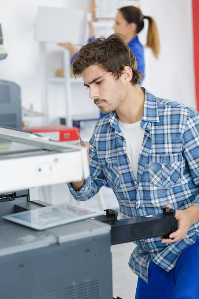 Jonge man een printer reparatie — Stockfoto