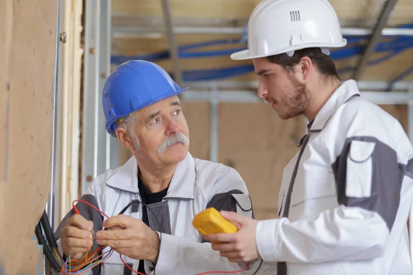 Constructeurs utilisant un multimètre jaune pour calibrer la maison — Photo