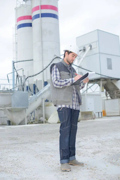 Man on construction site writing on clipboard — Stock Photo, Image