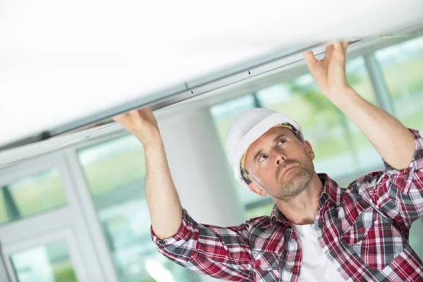 Trabalhador da construção masculina ajustando parte do teto — Fotografia de Stock