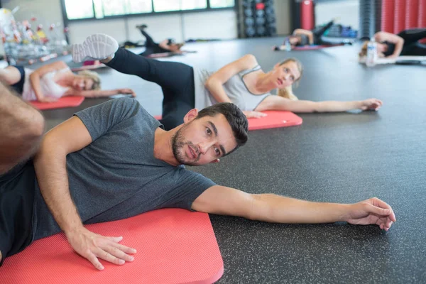 Lábak nyújtás egy fitness osztályban emberek — Stock Fotó