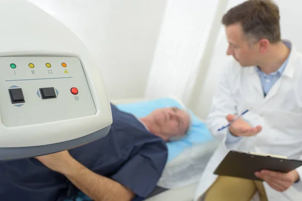 Médico explicando procedimento scanner para paciente sênior — Fotografia de Stock