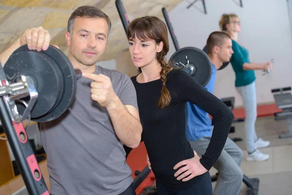 Trainer uitleg over het gebruik van opleiding machine in een sportschool — Stockfoto