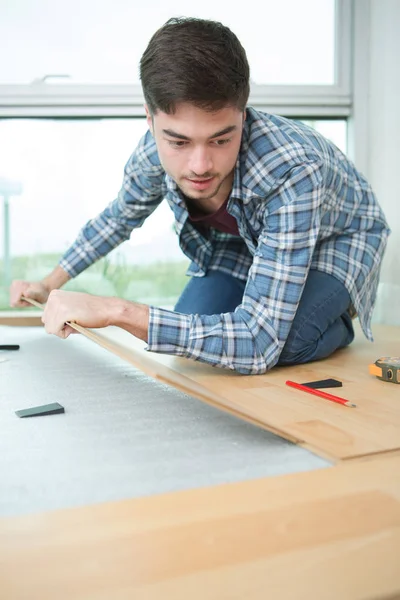 Young handsome male carpenter lying parquet flooring — Stock Photo, Image