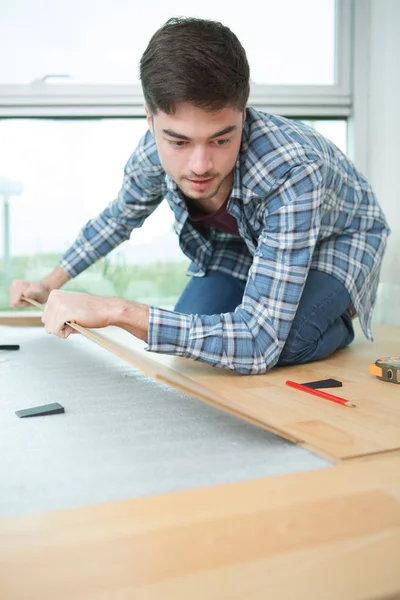 Fiatal jóképű férfi carpenter feküdt parketta — Stock Fotó