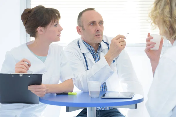 Ärzte und Krankenschwester sitzen entspannt im Büro — Stockfoto