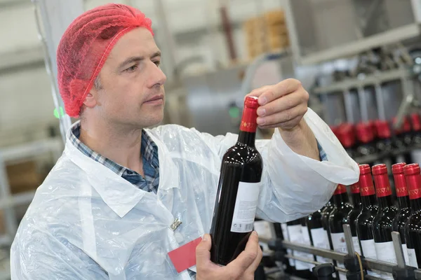 Macho adulto sosteniendo una botella de vino recién producida — Foto de Stock