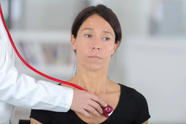 Médica fêmea ouvindo batimento cardíaco de paciente com estetoscópio — Fotografia de Stock