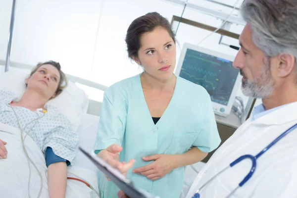 Arzt und Krankenschwester mit Klemmbrettern besuchen Patientin auf Krankenhausstation — Stockfoto