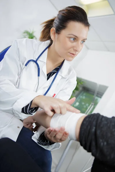 Female doctor bandaging mans injured hand — Stock Photo, Image