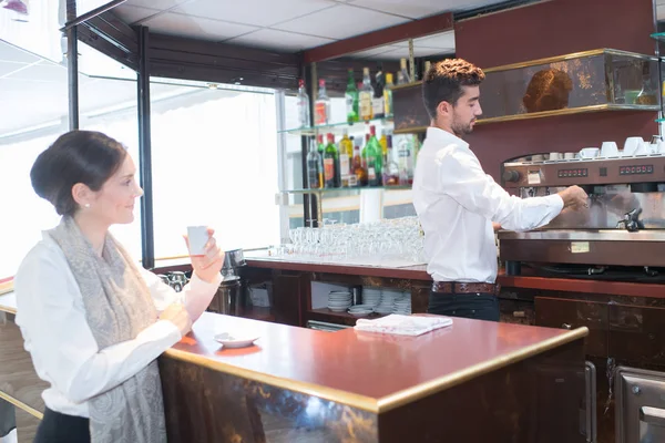 Młody mężczyzna barista porcję filiżankę kawy do klienta — Zdjęcie stockowe