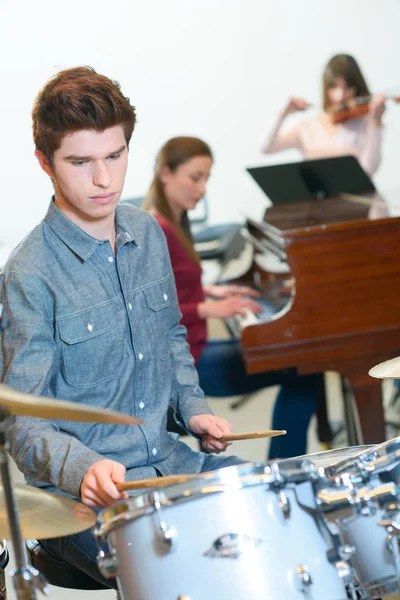 Молодий барабанщик з барабанними паличками в музичному класі — стокове фото