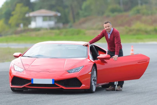 Homem e um carro vermelho Fotos De Bancos De Imagens Sem Royalties