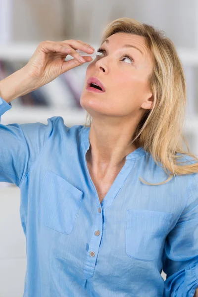一个女人把眼药水放在她的眼睛里 — 图库照片