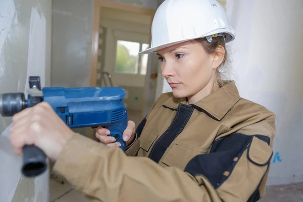 female construction worker drilling concrete wal