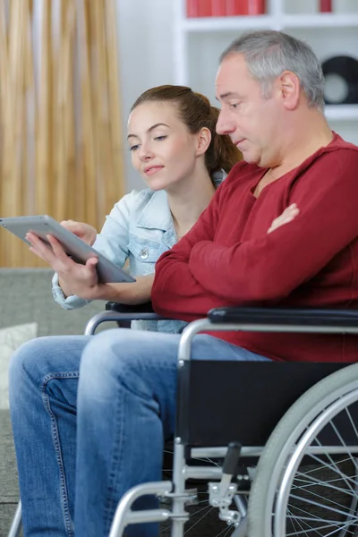 Giovane Donna Che Insegna Uomo Sulla Sedia Rotelle Con Tecnologia — Foto Stock