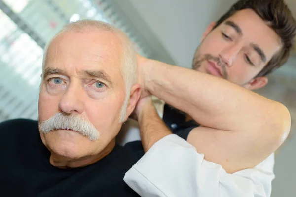 Fisioterapeuta Masculino Examinando Cuello Anciano — Foto de Stock