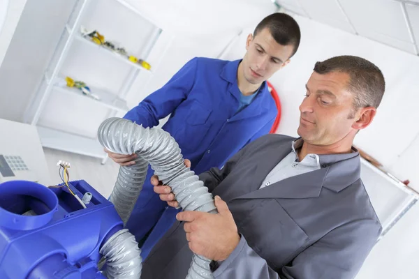 Uomini che installano un sistema di ventilazione al chiuso — Foto Stock