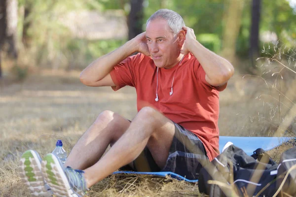 Hombre mayor haciendo abdominales en la naturaleza — Foto de Stock