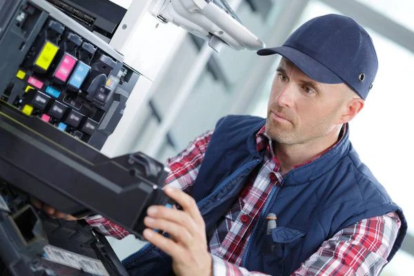 Homem técnico de reparação de uma impressora no local de trabalho — Fotografia de Stock