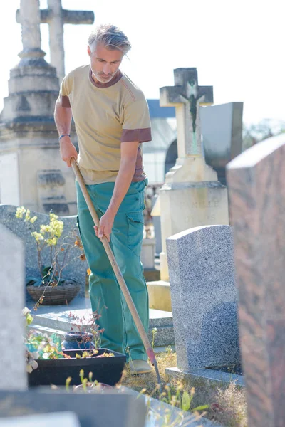 Homem capina em cemitério — Fotografia de Stock