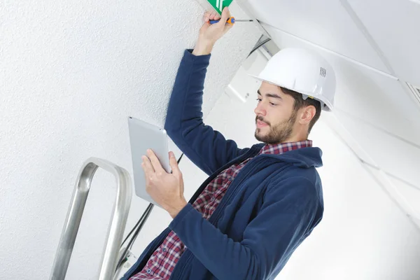 Electrician standing on a ladder and using a tablet — Stock Photo, Image
