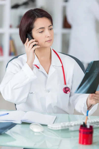 Kvinnliga läkare prata telefon i hennes kontor — Stockfoto