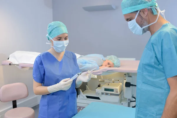 Jovem mulher médico segurando seringa paciente virado para baixo na maca — Fotografia de Stock