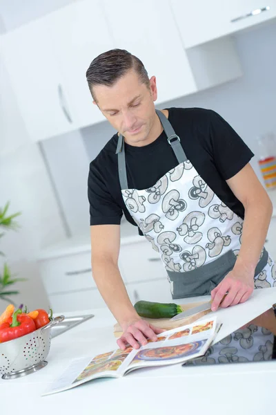 Man reading the procedures from the recipe book — Stock Photo, Image