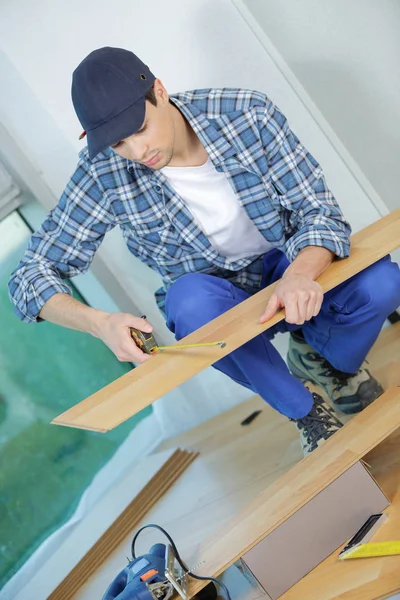 Junger Techniker verlegt Fußboden auf Baustelle — Stockfoto