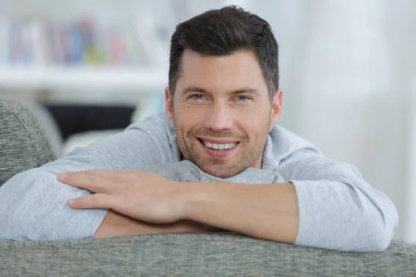 Lächelnder Mann, der zu Hause auf dem Sofa ruht — Stockfoto
