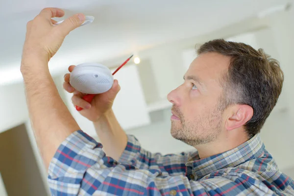 Elektricien montage een brandalarm — Stockfoto