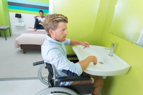 Hombre en silla de ruedas lavándose las manos en el baño —  Fotos de Stock