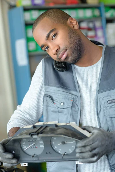 Mechanic fitting a dashboard in a car while using phone — Stock Photo, Image