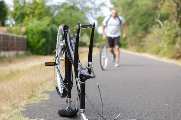 Man rollend wiel richting uitgesplitst fiets — Stockfoto