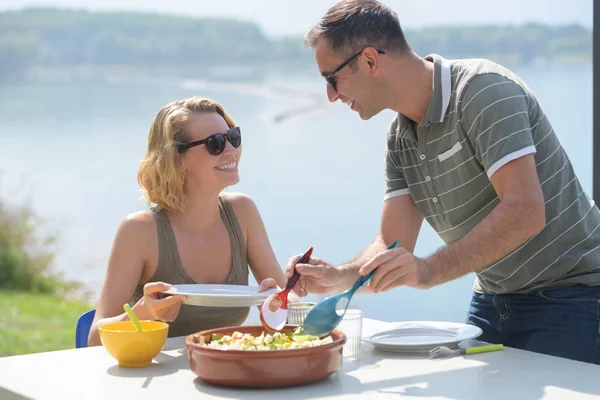 Giovane coppia mangiare un'insalata vicino a un lago durante l'estate — Foto Stock