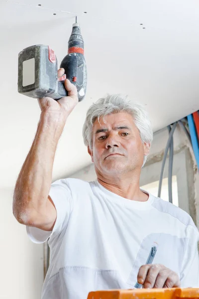 Viejo trabajador usando un taladro — Foto de Stock