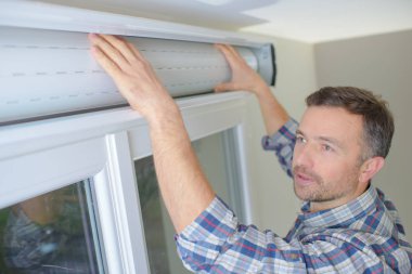 man installing cassette roller blinds on windows clipart