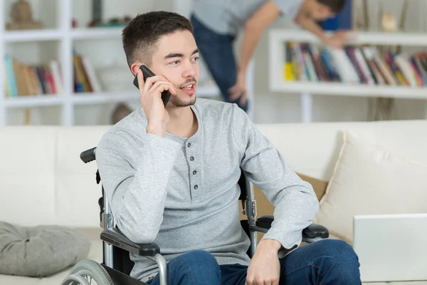 Chłopak na wózku inwalidzkim, przy użyciu telefonu komórkowego — Zdjęcie stockowe
